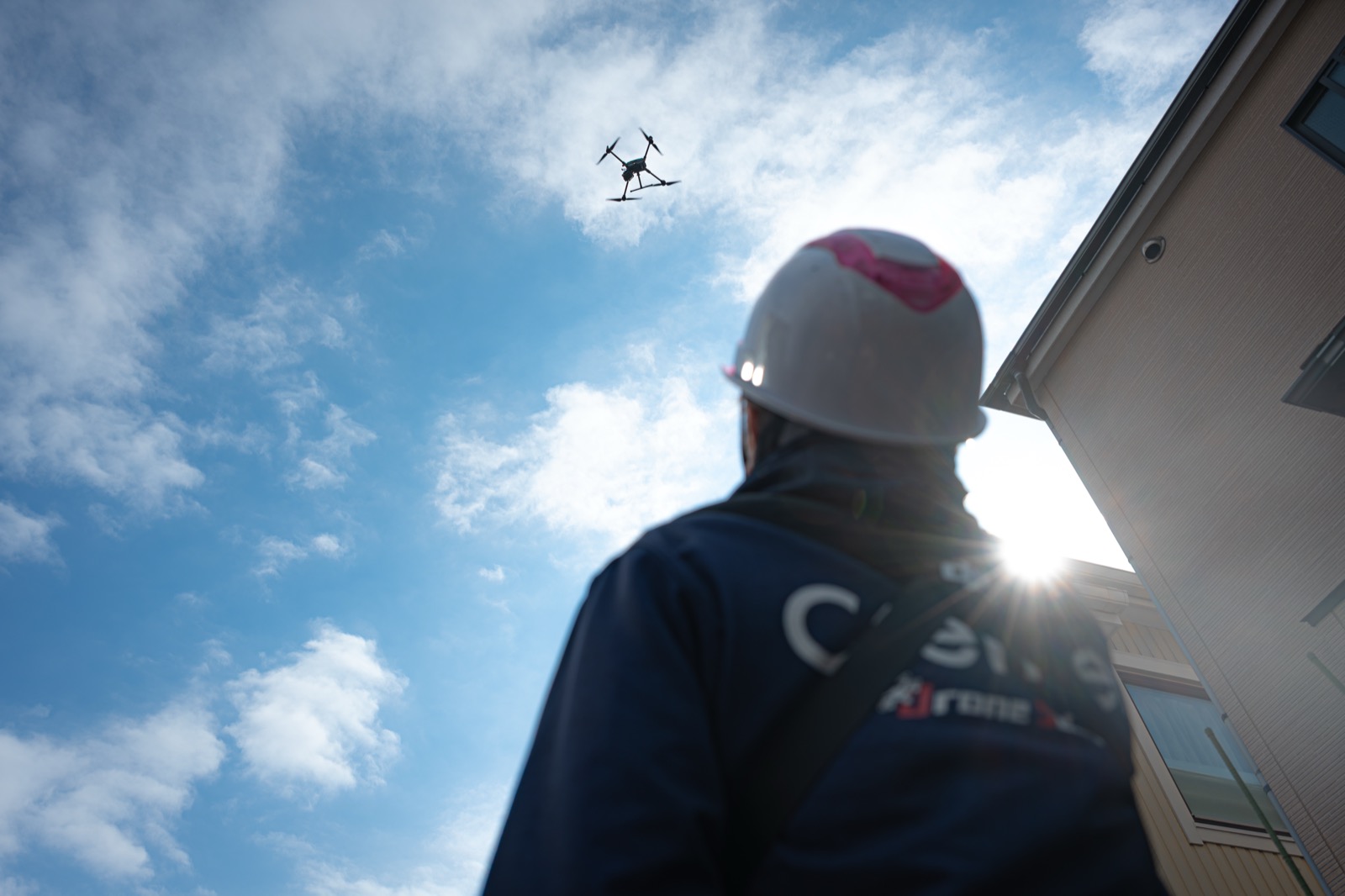 クレンセドローンスクールの受講者が青空の下でドローンを操縦している様子