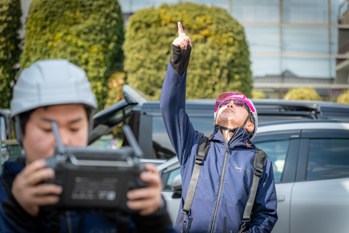 2名の受講生が現場で空を指差しドローンの安全確認を行っている様子